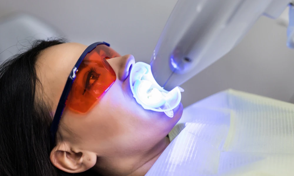 patient undergoing professional teeth whitening treatment with led whitening light