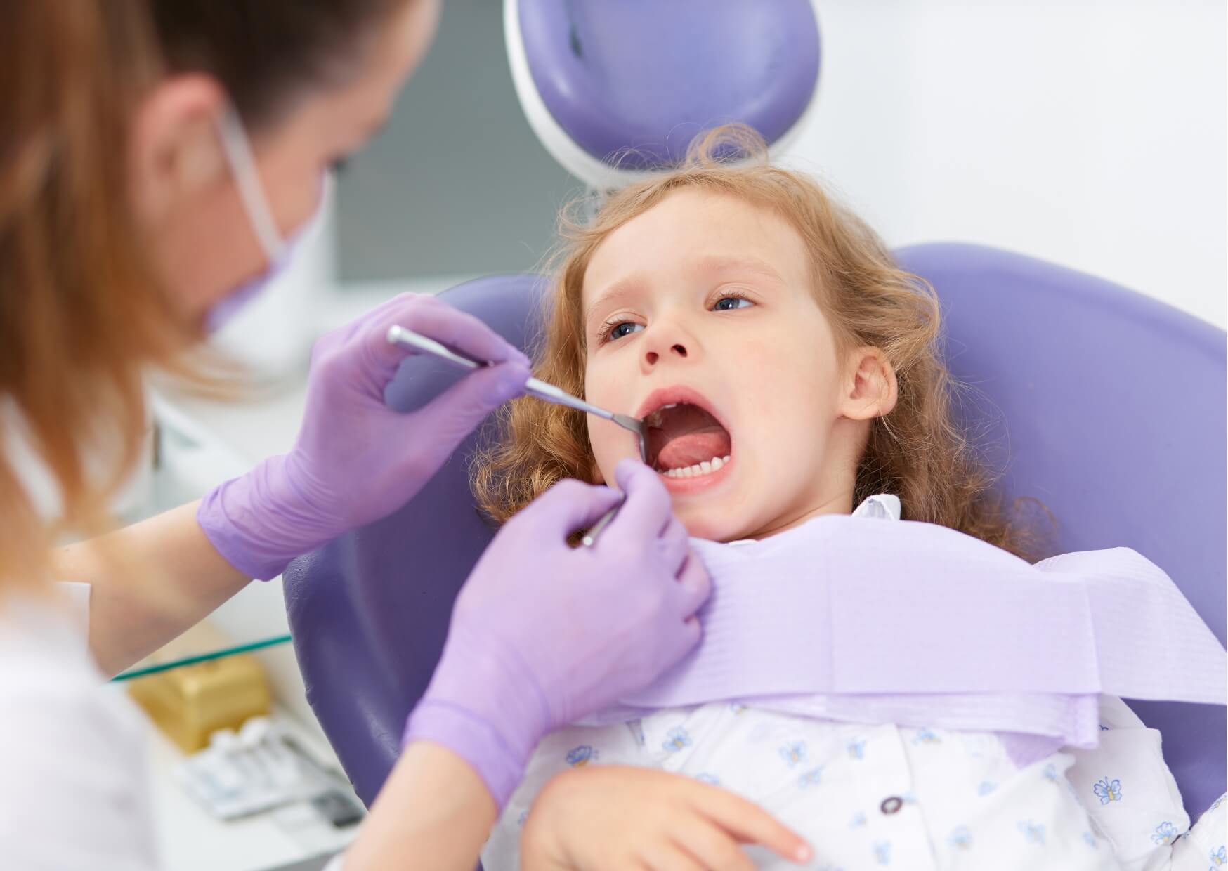 Pediatric dentist examining a child's teeth to determine whether a dental spacer is needed after early baby tooth loss.