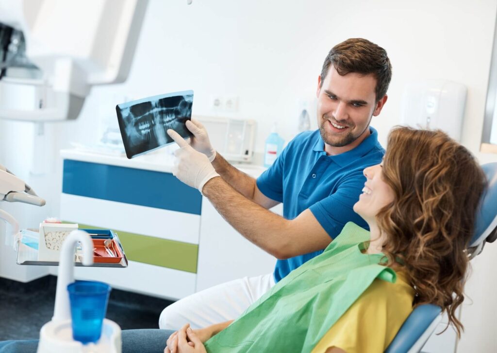 Dentist reviewing a dental X-ray with a patient to evaluate whether it is too late to get dental implants.