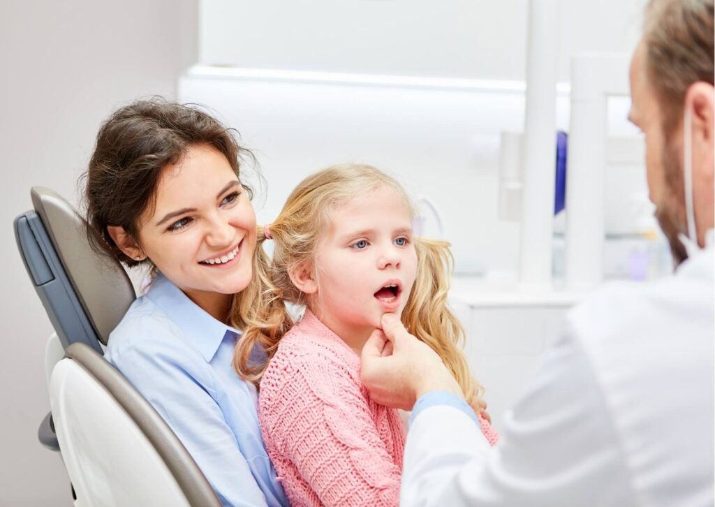 Dentist explaining kids dental spacers to a child and parent during a pediatric dental consultation.