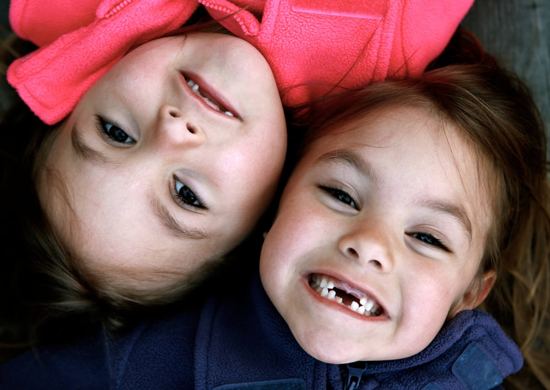 Two smiling children showing missing baby teeth, illustrating the typical age when kids lose their first tooth.