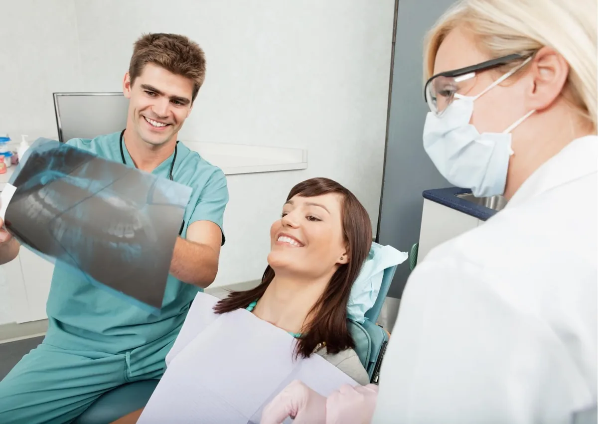 Dental team reviewing a patient’s X-ray to examine and count adult teeth during a dental visit.