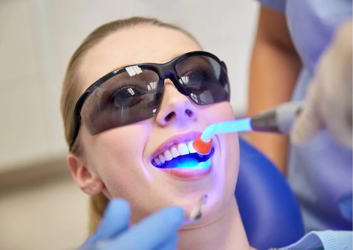 Patient receiving dental bonding treatment with a curing light as part of the overall tooth bonding cost.